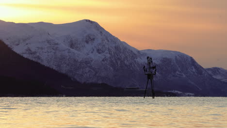 Navigation-mark-in-the-fjord-covered-with-cormorants-during-sunset