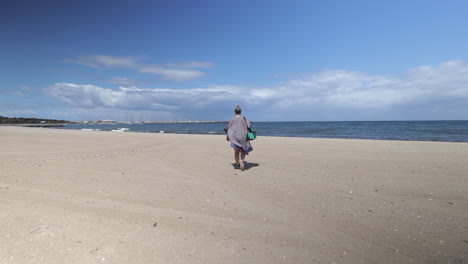 Woman-wearing-kimono-walking-towards-sea-on-Hampton-bay-beach,-Melbourne-Australia,-day-time-sunny,-Wide-shot