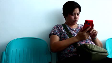 ANTIPOLO-CITY,-PHILIPPINES-–-JULY-12,-2019:-An-adult-Filipino-woman-uses-a-smartphone-while-sitting-on-a-bench-at-waiting-area