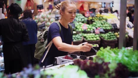 Young-woman-choosing-vegetables-for-lunch-in-a-salad-bar-at-a-shopping-mall-in-Asia