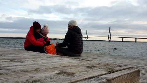 Hiking-family-having-picnic-and-enjoying-view-of-long-suspension-bridge