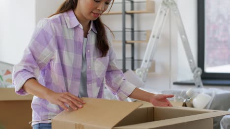 Women-with-Adhesive-Tape-Packing-Boxes-at-Home.moving,-people-and-real-estate-concept--women-with-adhesive-tape-packing-boxes-at-home