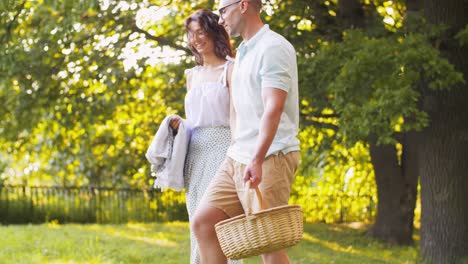 Happy-Couple-Laying-Picnic-Blanket-at-Summer-Park.leisure,-vacation-and-people-concept--happy-couple-laying-picnic-blanket-at-summer-park