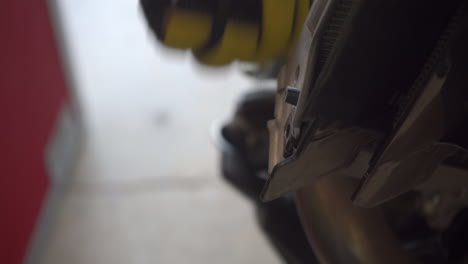 Gloved-hands-seen-removing-a-bolt-fastener-on-a-motorcycle-with-a-driver---close-up