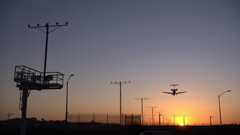 Airplane-Landing-From-Overhead-Into-Orange-Sunset