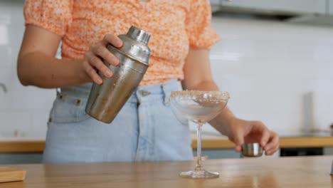 Frau-Mit-Shaker-Gießt-Cocktail-Ins-Glas.-Getränke-Und-Personen-Konzept.-Junge-Frau-Mit-Shaker-Gießt-Cocktail-Ins-Glas-In-Der-Küche-Zu-Hause