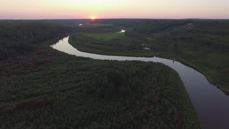 Eine-Drohne-Fliegt-Bei-Sonnenuntergang-Langsam-über-Ein-Ruhiges,-Gewundenes-Flusstal