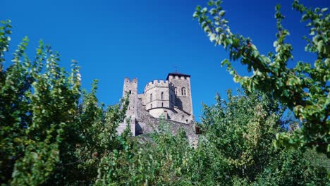 Truck-shot-of-European-medieval-castle-tower-through-green-bushes-in-summer