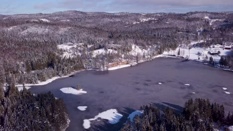 Luftaufnahme-Einer-Drohne-Mit-Blick-Auf-Einen-Zugefrorenen-Teich,-Hügel-Und-Wald-An-Einem-Sonnigen-Wintertag-In-Risvann,-Birkeland,-Agder,-Südnorwegen