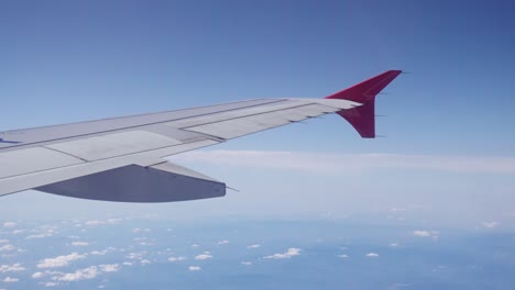 Plane`s-wing-on-blue-sky-background---view-from-airplane`s-window,-high-over-the-clouds