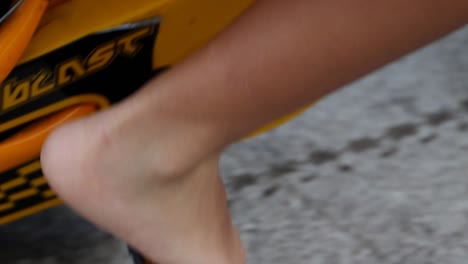 Detail-Close-up-shot-of-a-boy-barefoot-riding-a-small-yellow-bicycle