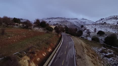 Vista-Aérea-Del-Paisaje-Sobre-Las-Carreteras-Nevadas-Y-Las-Altas-Montañas.