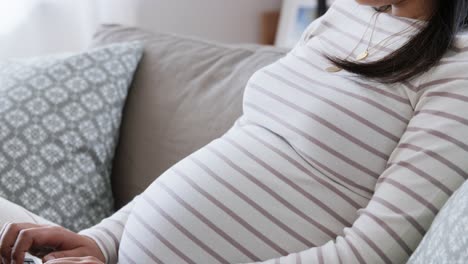 Happy-Pregnant-Asian-Woman-with-Laptop-at-Home.pregnancy,-rest,-people-and-expectation-concept--happy-smiling-pregnant-asian-woman-with-laptop-computer-sitting-on-sofa-at-home