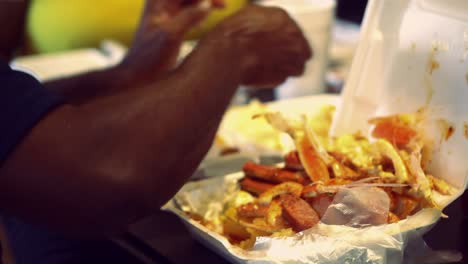 African-American-man-sits-eating-seafood-feast-while-out-with-his-friends-and-family