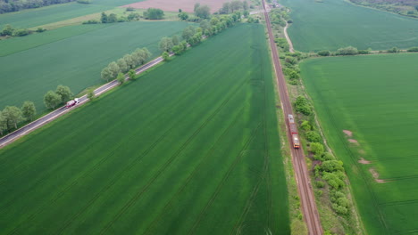 Sky-view-of-a-rail-track-with-train-passing-by-and-a-truck-on-the-concrete-road