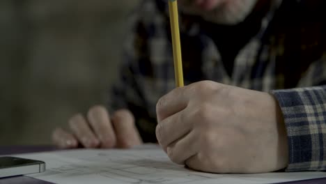 Close-up-shot-of-sketch-artist-drawing-on-sketch-paper-with-pencil-on-tope-of-purple-table