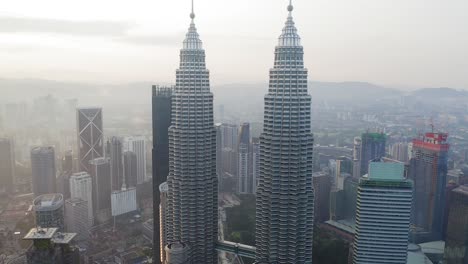 Kuala-Lumpur-at-Sunrise,-Aerial-view-of-the-City-skyline-passing-between-the-famous-Petronas-twin-towers,-Malaysia