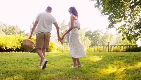 Feliz-Pareja-Colocando-Una-Manta-De-Picnic-En-El-Parque-De-Verano.-Concepto-De-Ocio,-Vacaciones-Y-Personas.-Feliz-Pareja-Colocando-Una-Manta-De-Picnic-En-El-Parque-De-Verano.