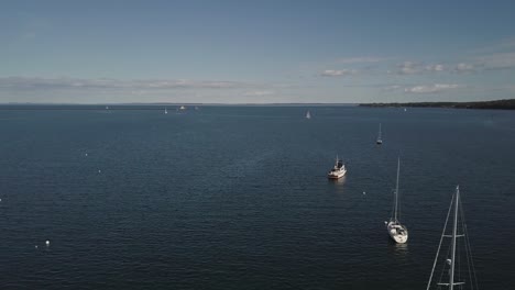 Aerial-Drone-Shot-Flying-Over-Several-Sailboats-In-Rockland-Harbor-In-Maine-Toward-Ocean