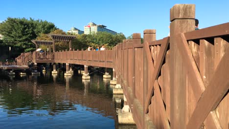 People-walk-over-a-wooden-bridge-at-Hosu-Park,-Janghang-dong,-Ilsan-gu,-Goyang-si,-Gyeonggi-do,-South-Korea