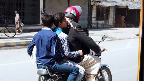 On-Ride-Slow-Motion-Shot-Of-A-Man-and-Two-Children-With-No-Helmet-on-a-Motor-Bike-in-Lahore,-Pakistan