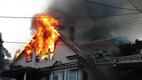 The-Roof-of-a-Wooden-House-Engulfed-in-Flames-with-Firefighters-on-the-Scene