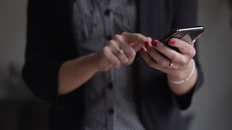 Female-office-worker-with-red-nails-sends-a-message-on-a-mobile-cell-phone