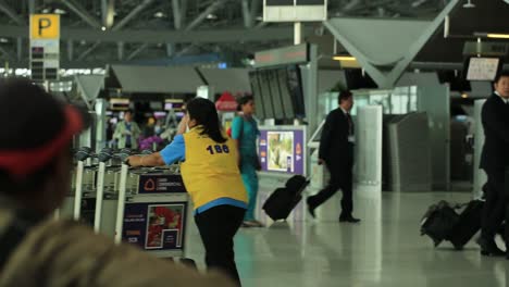 Suvarnabhumi-Airport-In-Bangkok,-Thailand---Staff,-Airplane-Crews,-Thais,-And-Tourists-Walking-Inside-The-Airport-Lounge-With-Their-Luggages-And-Carts---Close-up-Shot