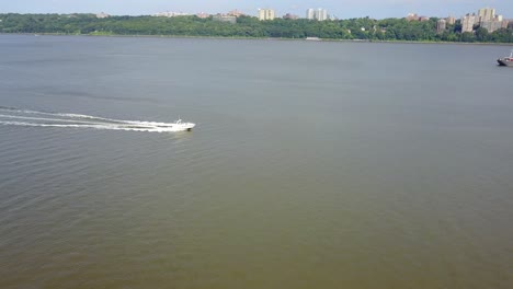 Drone-Boat-Follow-in-Hudson-River,-New-York-City-Reveal---Manhattan-and-Yonkers-Background,-Sunny-Day