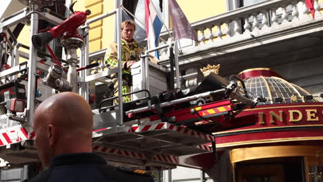 Cuerpo-De-Bomberos-Con-Grúa-Mecánica-Retirando-A-Un-Paciente-En-Camilla-De-Una-Habitación-De-Hotel-En-El-Segundo-Piso-En-La-Haya-En-Hotel-Des-Indes