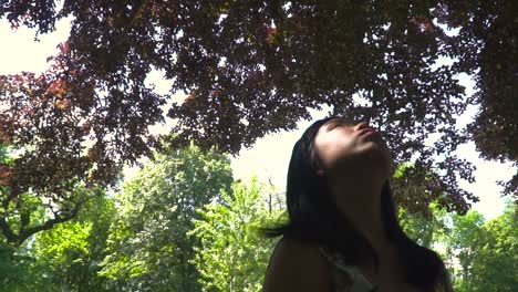 Rotating-view,-Asian-girl-looking-up-under-trees