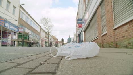 COVID19-deserted-English-high-street-with-a-plastic-bag-on-the-ground-blowing-gently-as-a-family-ride-past-on-push-bikes