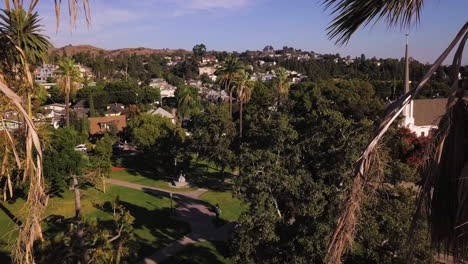 Central-Park-Historic-District,-gathering-place-of-the-Whittier,-California,-aerial-view-through-the-palms