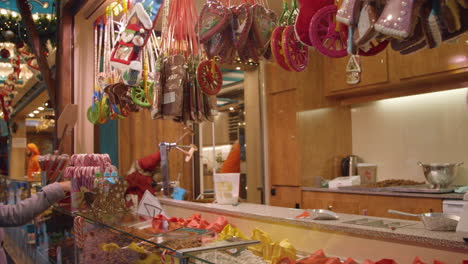 panning-down-shot-of-lady-workign-at-sweet-shop---kiosk-at-christmas-market