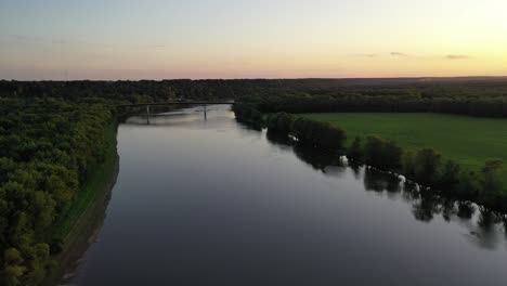 Empty-Bridge-and-Wide-River-in-Calm-Landscape,-Long-shot,-Aerial-Forward-Dolly