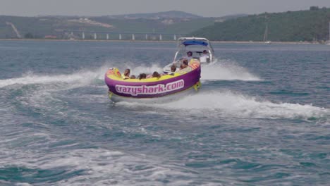 Motor-speedboat-pulls-inflatable-rubber-raft-with-people-jumping-waves