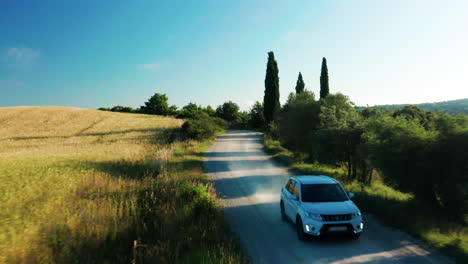 Car-drives-on-dirt-road-through-Tuscany-San-Quirico-d'Orcia-region