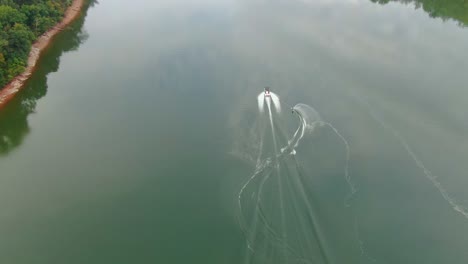 Aerial-view-of-water-skier-jumping-boat-wake-during-slalom-ride