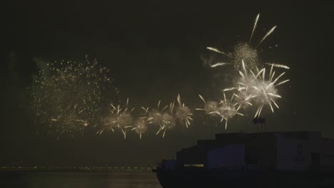 Großes-Feuerwerk,-Das-Auf-Dem-Meerwasser-Leuchtet,-Mit-Der-Silhouette-Des-Msheireb-Museums-Am-Wasser