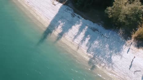 Perfect-turquoise-water-of-lake-with-white-beach-during-bright-sunny-day,-aerial