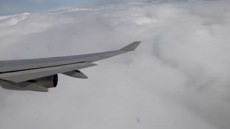 Flying-high-over-clouds-banking-right-in-large-jet-looking-out-right-window-at-wing