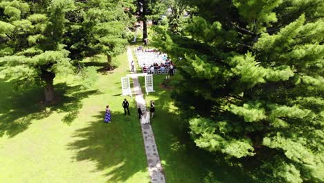 Drone-approaching-an-outdoor-wedding-with-guests-just-beginning-to-sit