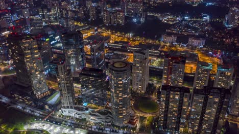 Hyperlapse:-colorful-scenic-night-lights-and-backward-flight-above-downtown-Sante-fe-city-center-skyscrapers,-buildings,-la-Mexicana-public-park,-shopping-mall-and-residential-community,-drone