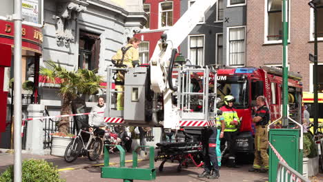 Fire-brigade-with-mechanical-crane-removing-a-patient-on-a-stretcher-from-a-hotel-room-on-the-second-floor-in-The-Hague-in-Hotel-des-Indes