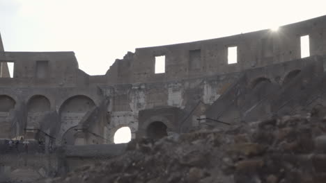 Pan-of-Sun-Disappearing-Behind-Colosseum-Wall-in-Rome,-Italy