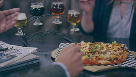 Eating-pizza-and-salad-with-with-friends-at-the-table-with-books-and-beer