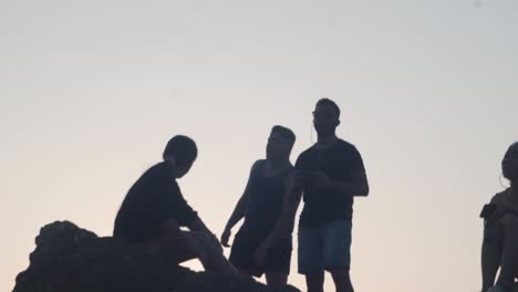 Silhouette-of-man-controlling-drone-with-group-of-friends-on-cliff-in-slow-motion,-Krabi-Thailand