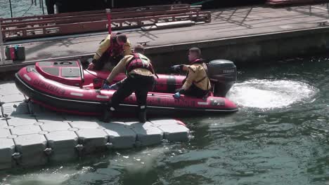 Four-young-Dublin-Fire-Brigade-men,-first-responders,-preparing-to-launch-an-inflatable-rescue-boat,-slow-motion