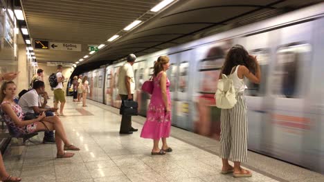 Una-Multitud-Esperando-El-Metro-Para-Llegar-A-La-Estación-De-Metro-En-Atenas,-Grecia,-El-Transporte-Se-Acerca-Y-Se-Detiene-En-La-Estación