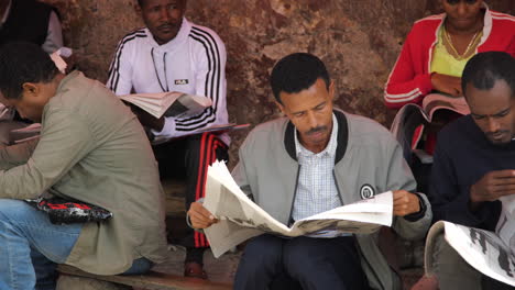 Ethiopians-reading-newspapers-and-looking-at-job-listings-on-a-street-in-Addis-Ababa,-Ethiopia